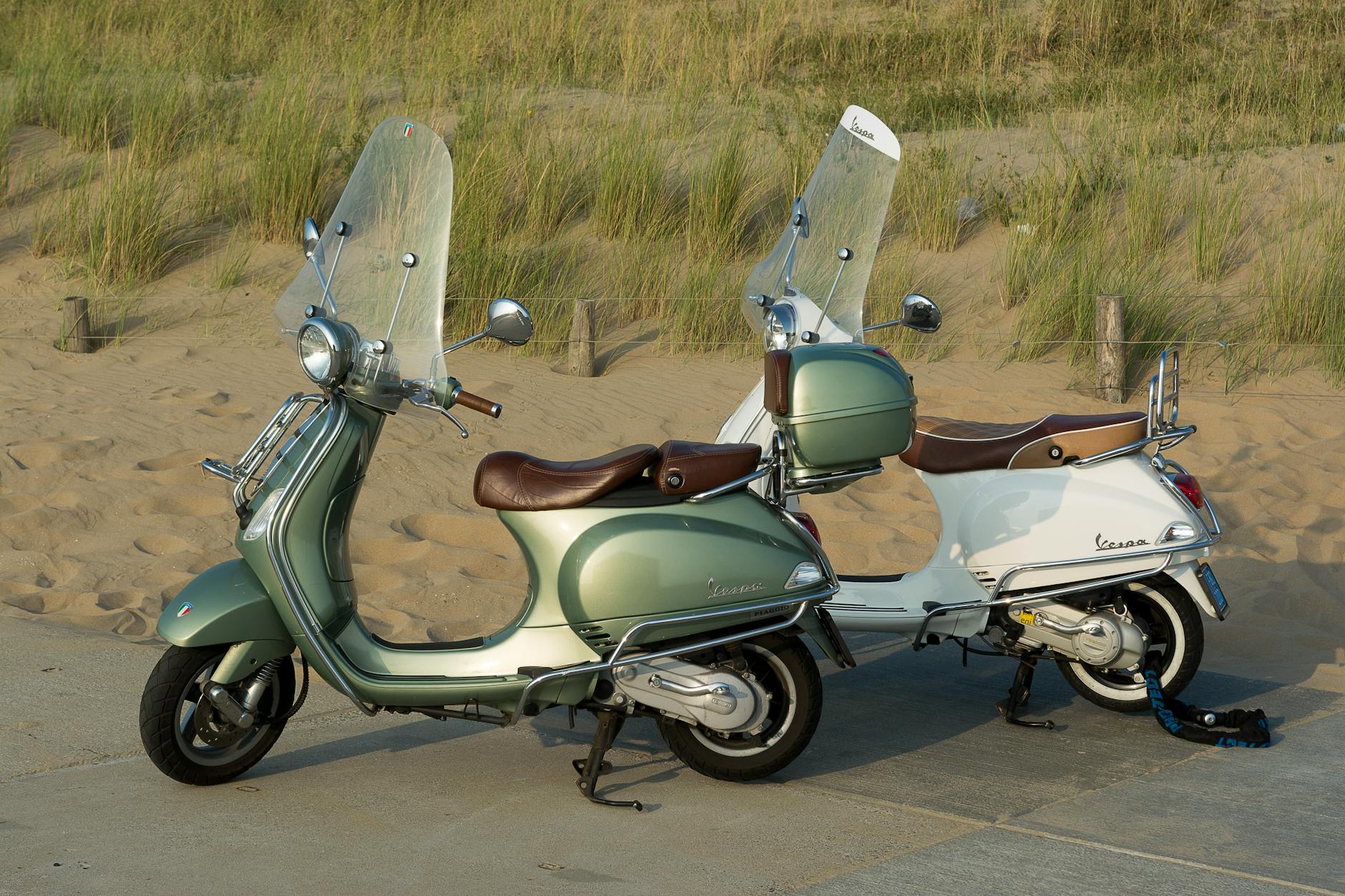 Skutery klasyczne zaparkowane przy plaży z wydmami w tle