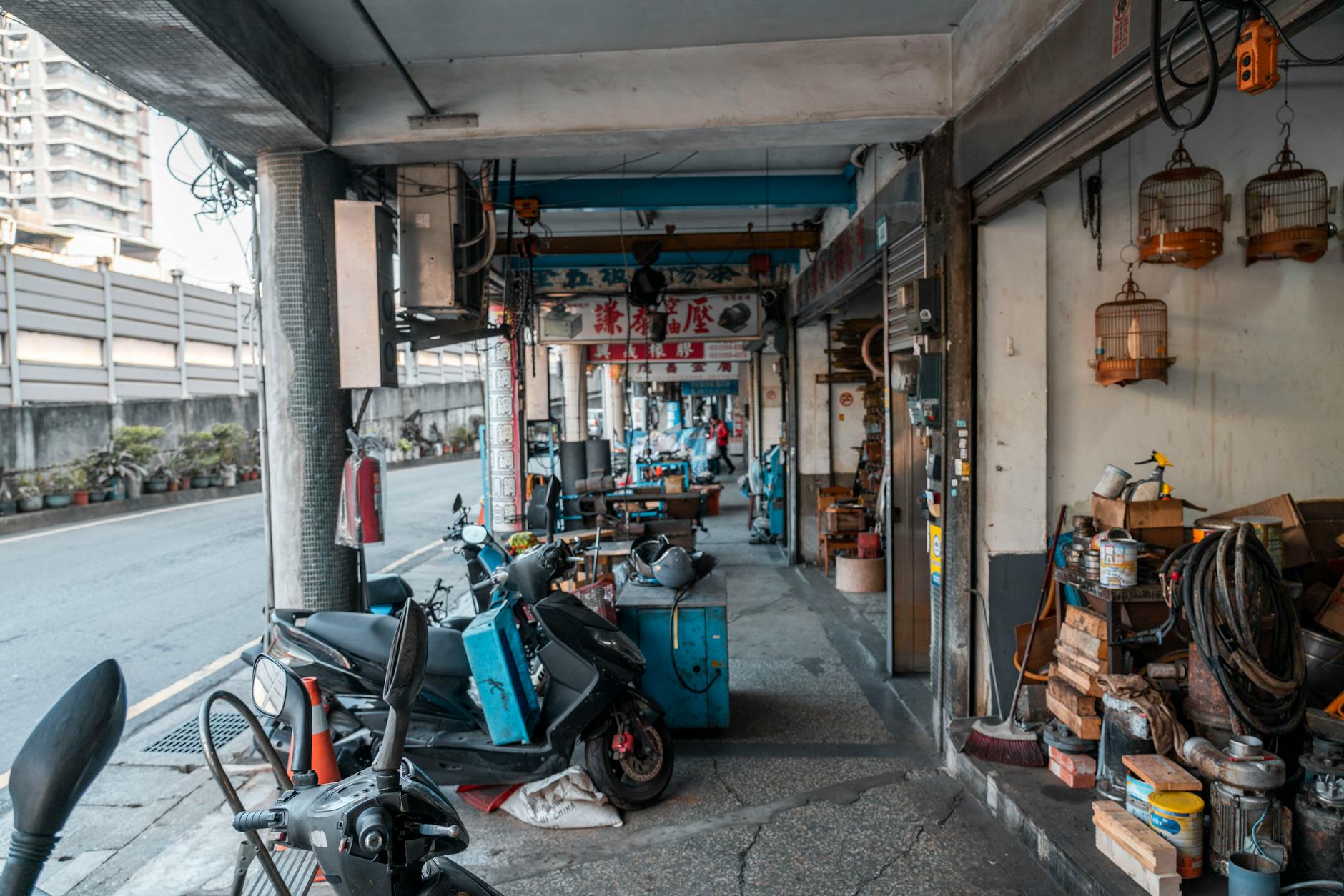 Skutery zaparkowane w miejskiej alejce obok warsztatu