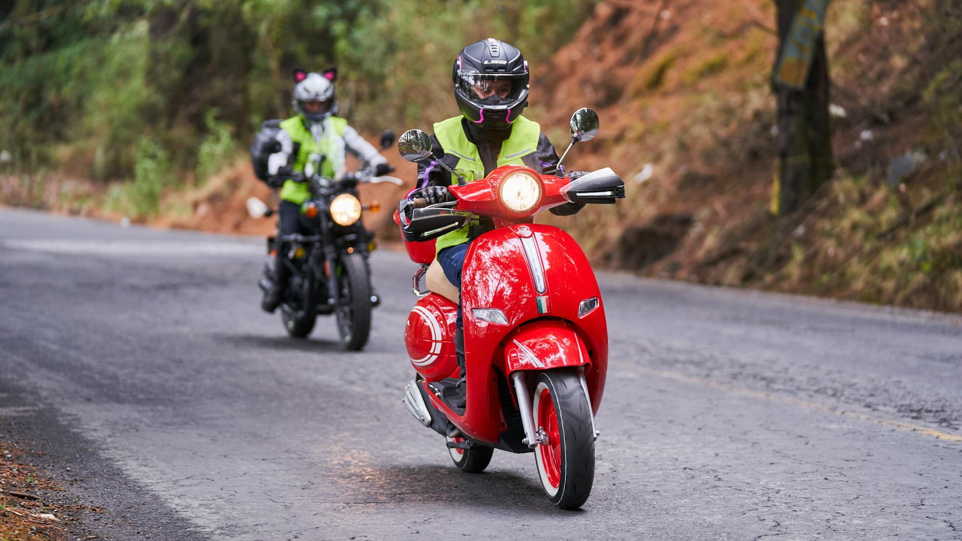 Dwóch motocyklistów w odblaskach jedzie drogą przez malowniczy teren