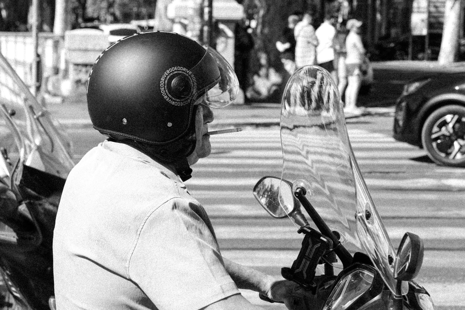 Starszy mężczyzna na skuterze Peugeot pali papierosa w miejskiej scenerii