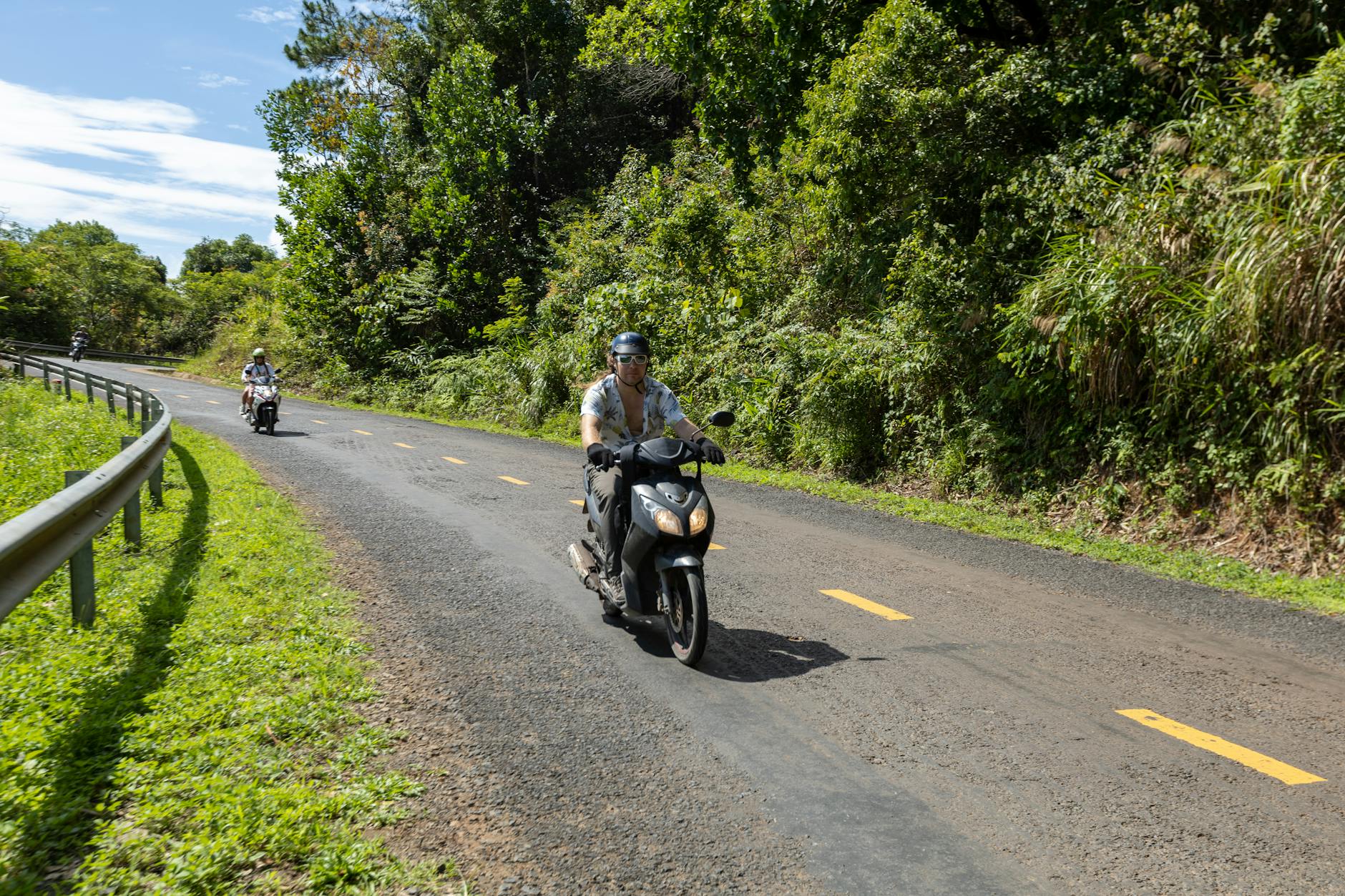Dwaj motocykliści jadą wiejską drogą otoczoną zielenią