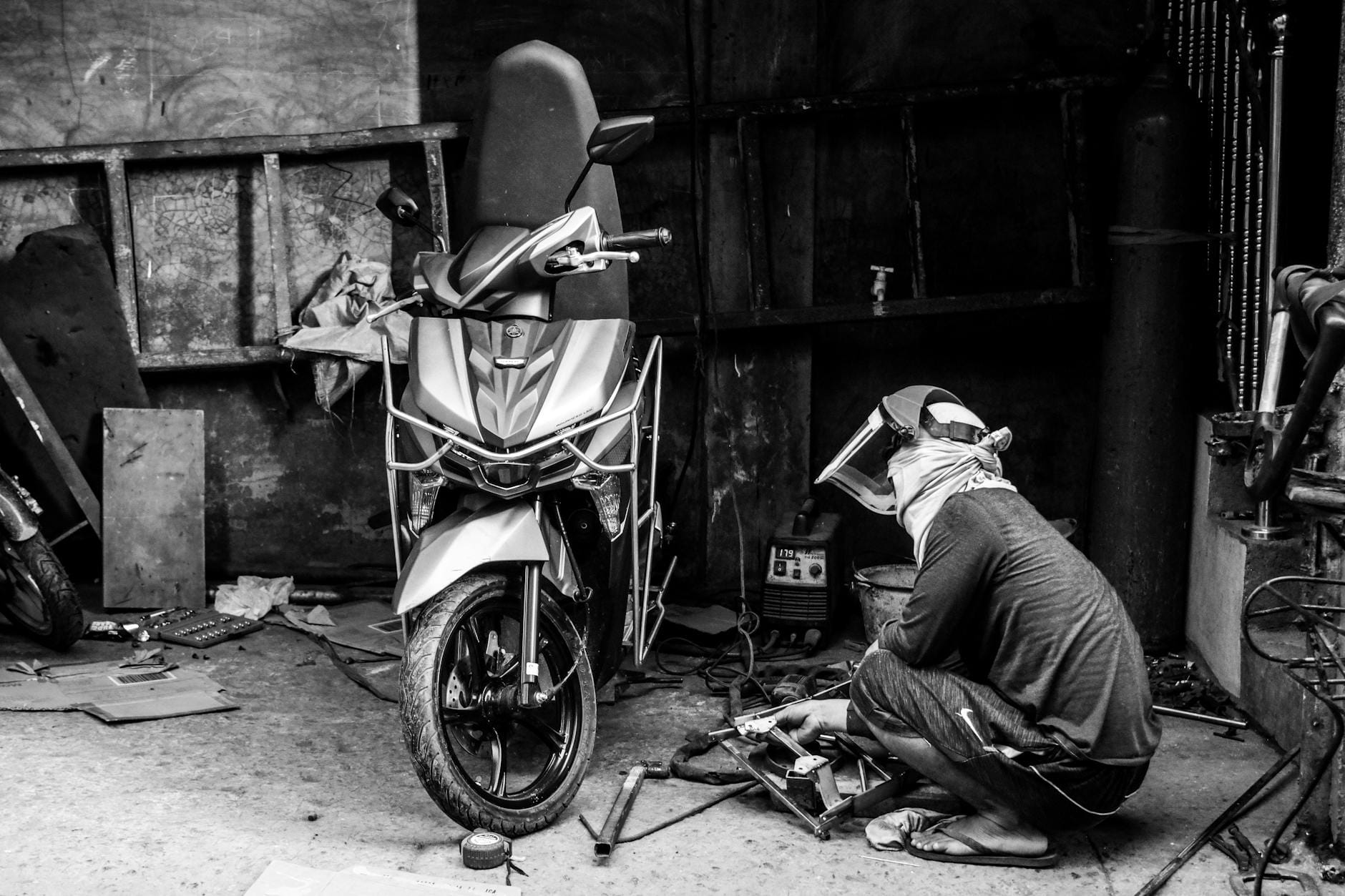 Spawacz naprawiający skuter w warsztacie, zdjęcie czarno-białe