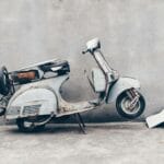 Stary zardzewiały skuter oparty o betonową ścianę